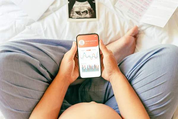 Pregnancy health app. Pregnant woman holding smartphone. Mobile pregnancy online maternity application. Concept of pregnancy, maternity, expectation for baby birth