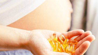 Annelik takviyesi hapı. Mutlu gülümseyen kadın Omega 3 vitamini ile hap alıyor. Hamilelik, ilaç sağlık konsepti