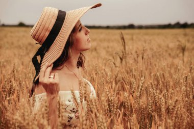 Woman field wheat. Happy young woman in sun hat in summer wheat field at sunset. Nature, summer holidays, vacation and people concept