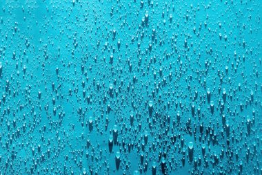 Su mavi arkaplanı düşürür. Damlacık yağmur dokusu sıçratıyor. Su sıçratma deseni. Seçici odak