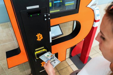 ATM Bitcoin veznedarı. Kadın Amerikan Doları 'ndan para çekiyor. Sanal kripto para birimi btc cüzdanı için 100 dolar. Bitcoin BTC ATM Para Makinesi
