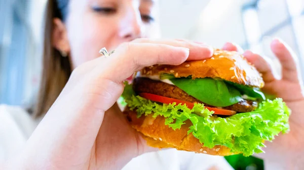 Vegetarian hamburger healthy vegan burger. Cute cheerful girl eating veggie sandwich with salad, avocado, vegetable. Vegan burger healthy diet food