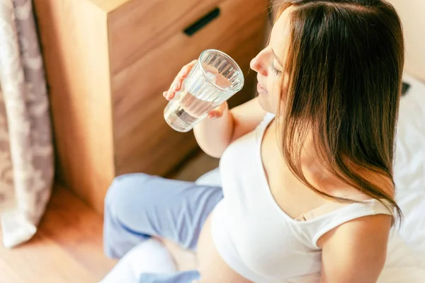 Pregnant drinking woman. Beautiful pregnancy drink water. Happy pregnant lady holding glass of water. Concept of maternity, expectation