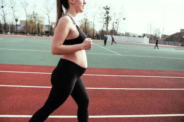 Hamilelik eğitimi. Hamile kadın yoga sporu antrenmanı yapıyor. Dışarıda doğum öncesi sağlıklı spor salonu var. Doğum öncesi egzersizleri.