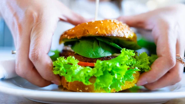 Vegan sandwich healthy vegetarian burger. Cute cheerful girl eating veggie hamburger with salad, avocado, vegetable. Vegetarian diet food concept