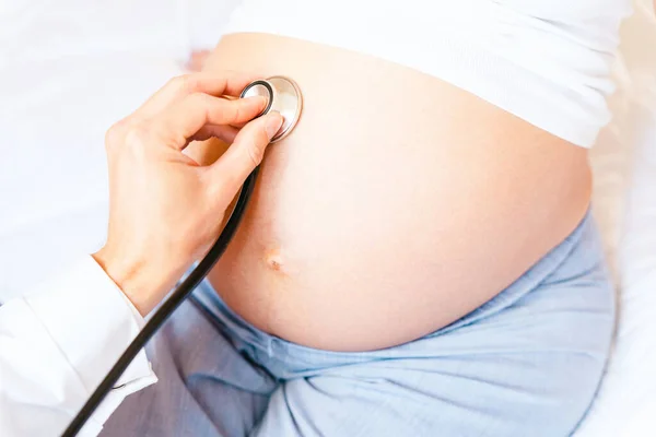 Pregnant consult doctor. Medical clinic for pregnancy consultant. Doctor examining pregnancy woman belly holding stethoscope. Concept of pregnancy, maternity, expectation for baby birth