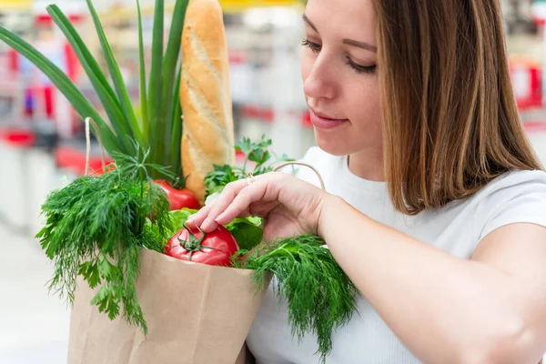 Pregnant supermarket food bag. Pregnancy woman with healthy fruit, fresh tomato in market food bag on grocery supermarket background. Shopping food supermarket concept