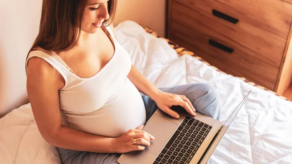 Pregnancy computer app. Pregnant woman holding digital laptop. Mobile pregnancy online maternity notebook application. Concept maternity, pregnancy, childbirth