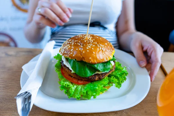 Veggie burger healthy vegan food. Salad, avocado, vegetable on vegetarian hamburger eating cute woman. Vegan sandwich healthy diet food