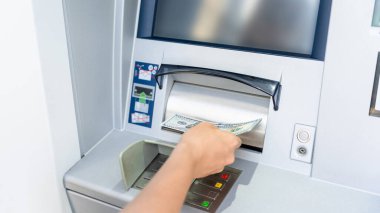 ATM ekranı. Amerikan banknotlarını elinde tutuyor. Kadın, 100 dolar çekmiş. Para yığını, banka kartı.