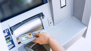 ATM 'den nakit para. Kadın para çekme faturası. 100 Amerikan Doları 'nı elinde tutuyor. Banka kredi kartı ve dolar faturası
