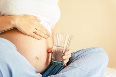 Hamile içme suyu. Güzel hamilelik içme suyu. Elinde bir bardak su tutan mutlu hamile kadın. Hamilelik, annelik, sağlık konsepti