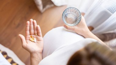 Sağlık, tedavi, takviye malzemeler. Mutlu gülümseyen kadın Omega 3 vitamini ile hap alıyor. Hamilelik, ilaç sağlık konsepti