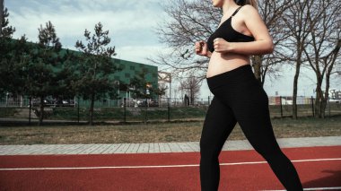 Doğum öncesi egzersizleri. Dışarıda doğum öncesi sağlıklı spor salonu var. Hamile kadın yoga sporu antrenmanı yapıyor. Hamilelik eğitimi