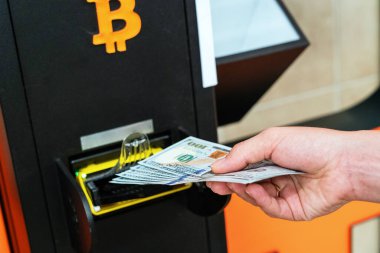 ATM Bitcoin veznedarı. Kadın Amerikan Doları 'ndan para çekiyor. Sanal kripto para birimi btc cüzdanı için 100 dolar. Bitcoin BTC ATM Para Makinesi
