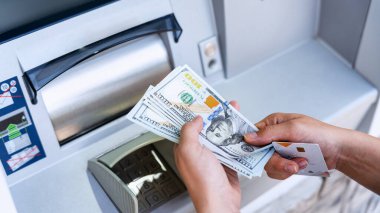 ATM 'den nakit para. Kadın para çekme faturası. 100 Amerikan Doları 'nı elinde tutuyor. Banka kredi kartı ve dolar faturası