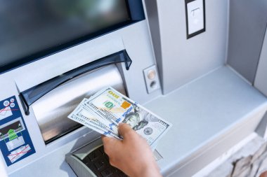 ATM 'den nakit para. Amerikan banknotlarını elinde tutuyor. Kadın, 100 dolar çekmiş. Amerikan doları, banka kartı.