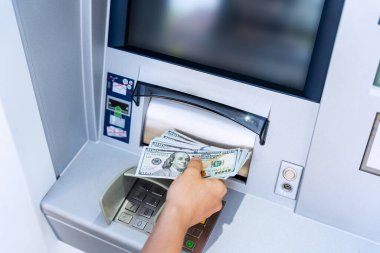 ATM ekranı. Amerikan banknotlarını elinde tutuyor. Kadın, 100 dolar çekmiş. Para yığını, banka kartı.