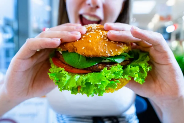 Vegetarian hamburger healthy vegan burger. Cute cheerful girl eating veggie sandwich with salad, avocado, vegetable. Vegan burger healthy diet food