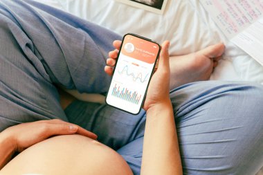 Hamilelik sağlık uygulaması. Elinde akıllı telefon tutan hamile bir kadın. Taşınabilir hamilelik çevrimiçi annelik başvurusu. Hamilelik kavramı, annelik, bebek doğumu beklentisi