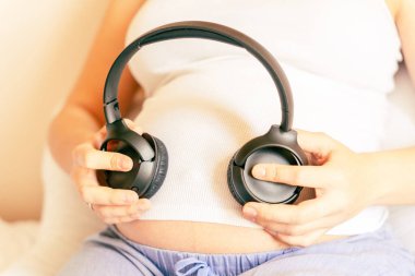 Hamilelik terapisi müziği. Müzik dinleyen hamile bir kadın. Anne göbek kulaklık sesi duyuyor. Hamilelik, ilaç sağlık hizmetleri ve insanların konsepti