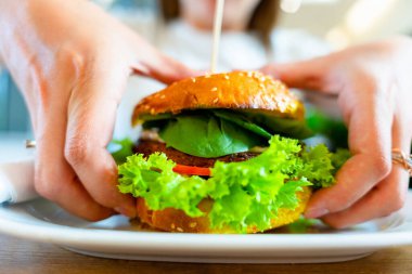 Hamburger vejetaryen sağlıklı vejetaryen burger. Salata, avokado, sebzeli sandviç ve tatlı bir kadın. Lezzetli vejetaryen sağlıklı yeşil yemek.