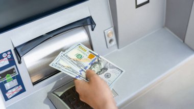 ATM 'nin parası. Kadın para çekme faturası. İçinde 100 Amerikan doları var. Para doları, banka kartı.