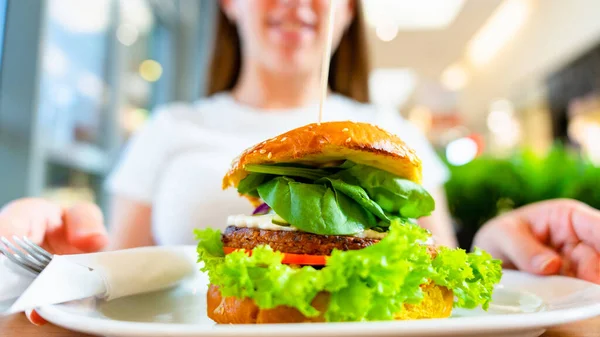 Vegan sandwich healthy vegetarian burger. Cute cheerful girl eating veggie hamburger with salad, avocado, vegetable. Vegetarian diet food concept