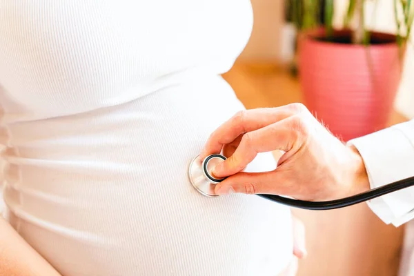 Doctor consultation pregnant woman. Medical clinic for pregnancy consultant. Doctor examining pregnancy woman belly holding stethoscope. Concept maternity, pregnancy, childbirth