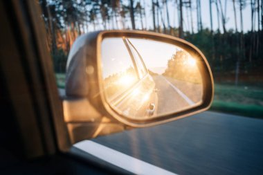 Car sunset road mirror. Summer sun, highway car road reflection in mirror. Vacation trip concept.