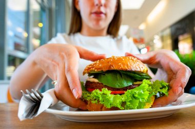 Veggie burger healthy vegan food. Salad, avocado, vegetable on vegetarian hamburger eating cute woman. Vegan sandwich healthy diet food