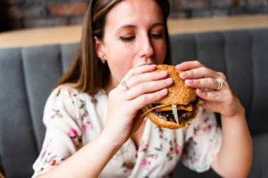 Woman hamburger eat. Hungry Caucasian Female Eating Tasty Burger. Fast food, people and unhealthy eating concept
