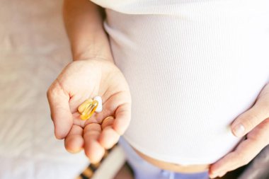 Doğum öncesi vitamin hapı. Mutlu gülümseyen kadın Omega 3 vitamini ile hap alıyor. D vitamini, E vitamini, Balık yağı kapsülleri