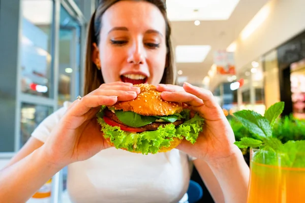 Vegetarian hamburger healthy vegan burger. Cute cheerful girl eating veggie sandwich with salad, avocado, vegetable. Vegan burger healthy diet food