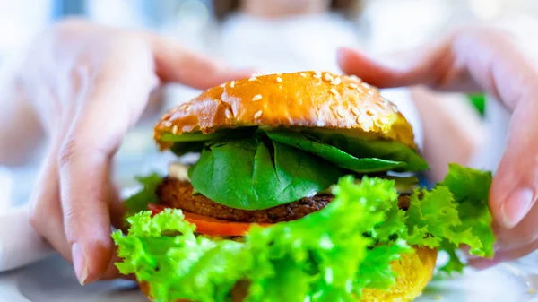 Hamburger vegan healthy vegetarian burger. Salad, avocado, vegetable on veggie sandwich eating cute woman. Tasty vegetarian healthy green food