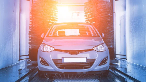 Auto car wash. Auto brush washer clean blue car on automatic carwash station. Automatic car wash background