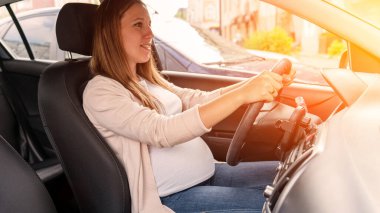 Woman driving car. Beautiful smiling pregnant woman driving car. Safety pregnancy young mother drive concept