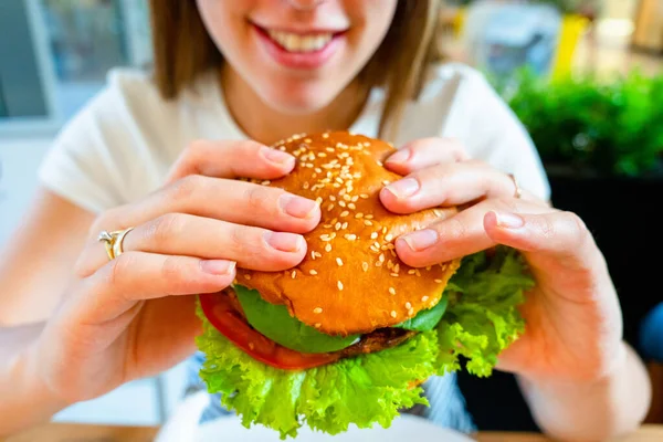 Veggie sandwich healthy vegan burger. Cute cheerful girl eating vegetarian hamburger with salad, avocado, vegetable. Hamburger vegan healthy diet food