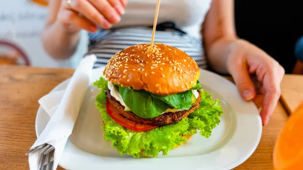 Hamburger vegan healthy vegetarian burger. Salad, avocado, vegetable on veggie sandwich eating cute woman. Tasty vegetarian healthy green food