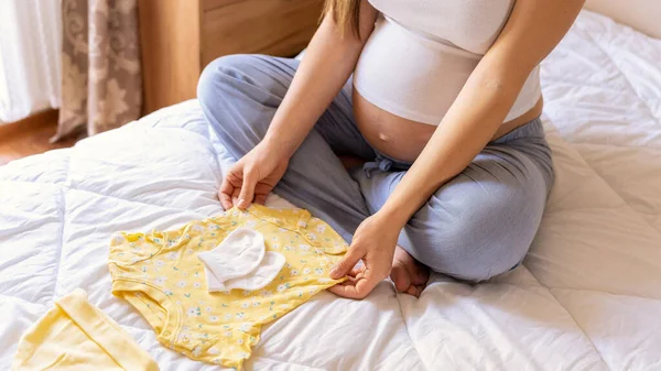 Kadın Bebek Kıyafetleri Sarı Bebek Kıyafetleri Tutan Mutlu Hamile Bir — Stok fotoğraf