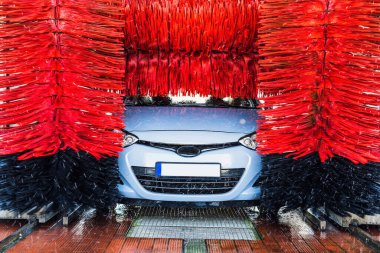 Araba yıkama makinesi. Otomatik yıkama istasyonunda otomatik fırçayla temizlenmiş mavi araba. Otomatik oto yıkama makinesi arkaplanı