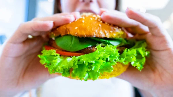 Hamburger vegan healthy vegetarian burger. Salad, avocado, vegetable on veggie sandwich eating cute woman. Tasty vegetarian healthy green food