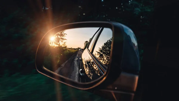 Road sunset car mirror. Summer sun, highway car road reflection in mirror. Vacation trip concept