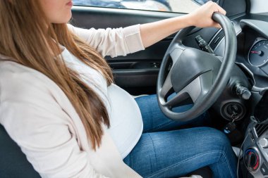 Pregnant driving car. Young smiling pregnancy woman driving car. Safety pregnant young mom driving concept