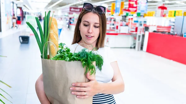 Pregnant healthy food bag. Pregnancy woman with healthy vegetables fresh, lettuce salad leaves in market food bag on grocery supermarket background. Healthy food background