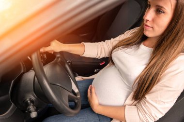 Pregnant driving car. Young smiling pregnancy woman driving car. Safety pregnant young mom driving concept