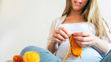 Pregnancy knitting baby winter clothes. Pregnancy mother crochet kid cloth. Cute pregnant woman knit fashion winter baby girl clothes. Warm winter cozy clothes for baby