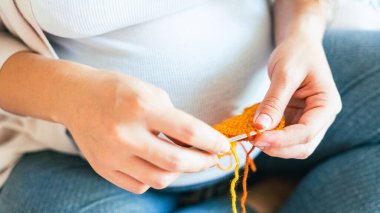 Woman knitting baby winter clothes. Cute pregnant woman knit fashion winter baby girl clothes. Pregnancy mother crochet kid cloth. Cozy knitting woman