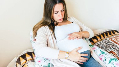 Pregnancy contractions time. Childbirth time, contractions pain. Pregnant holding baby belly, woman watching clock. Therapy, healthcare, motherhood concept