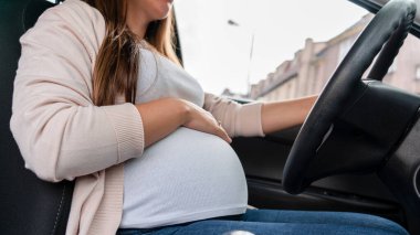 Pregnant driving car. Young smiling pregnancy woman driving car. Safety pregnant young mom driving concept
